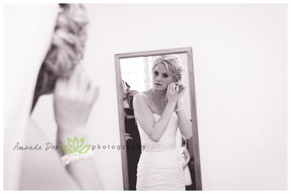 Wedding photo of bride getting ready putting on earrings in mirror