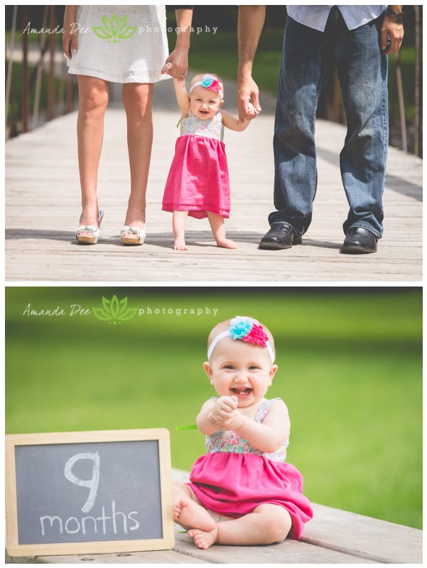 9 month baby girl with sign holding mom and dads hands standing